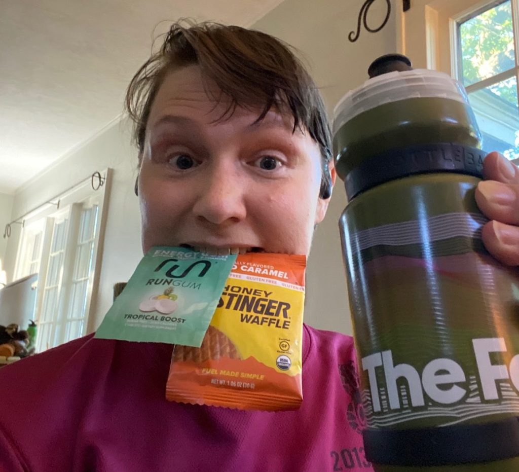 Bain holding Run Gum, a Honey Stinger waffle, and a water bottle from The Feed